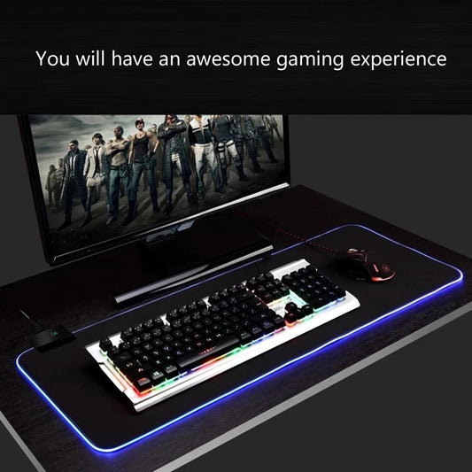 A large RGB gaming desk mat lit up on a desk with a keyboard and mouse.